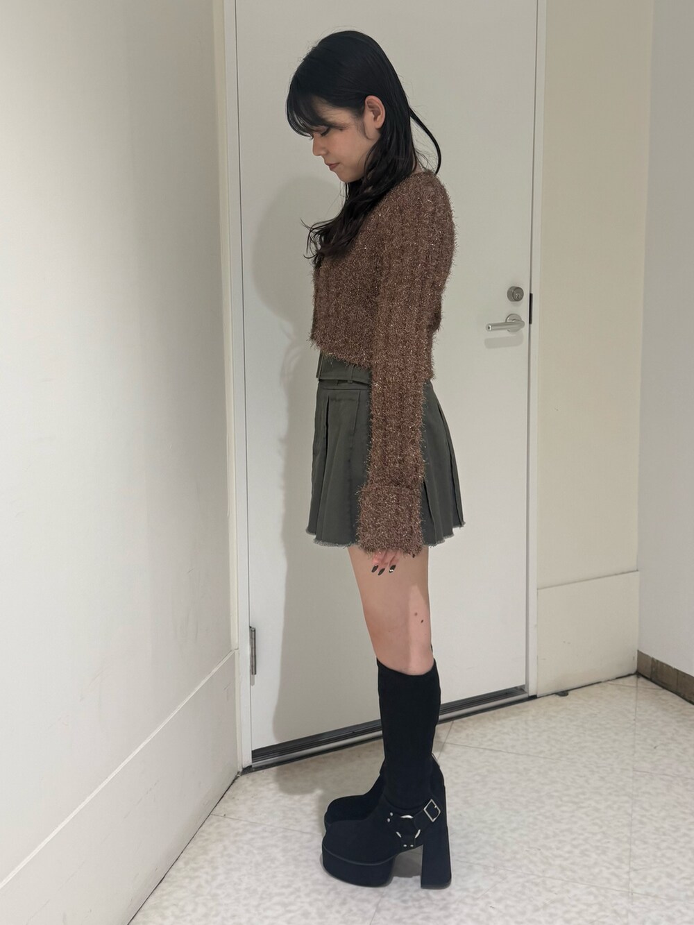 グレー系のスカート、ブラック系のブーツ、ブラウン系のカーディガン/ボレロを着用したレディースの秋コーディネートの2枚目の写真