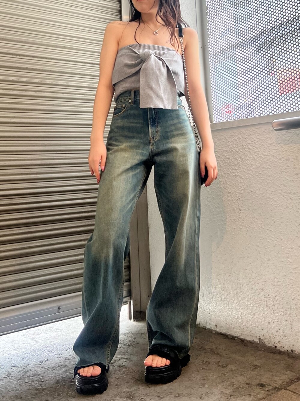 ブルー系のデニムパンツ、グレー系のキャミソール、ブラック系のショルダーバッグを着用したレディースの春コーディネートの2枚目の写真