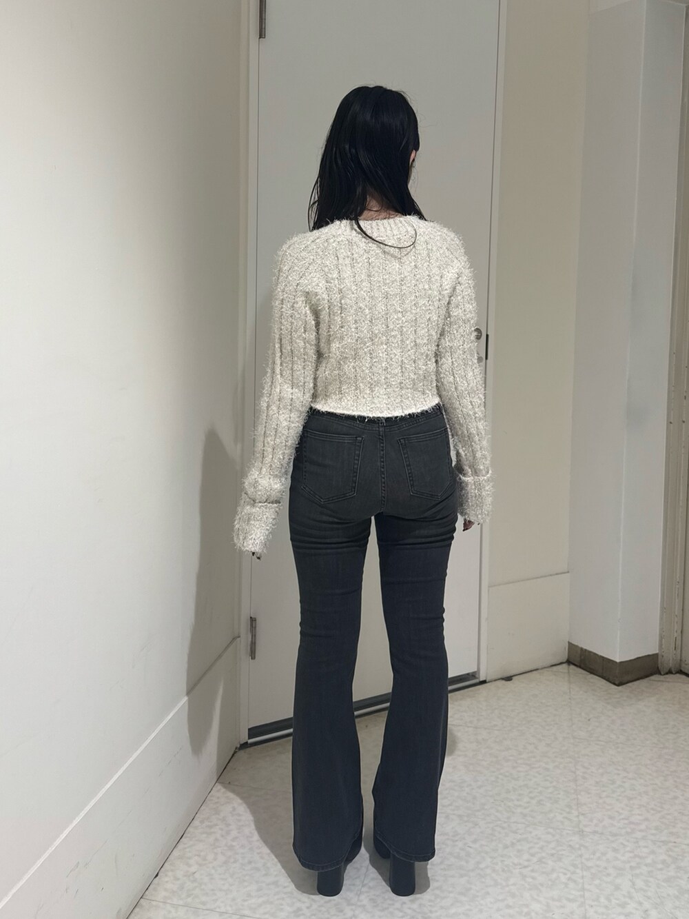 ブラック系のブーツ、ブラック系のデニムパンツ、ホワイト系のカーディガン/ボレロを着用したレディースの秋コーディネートの3枚目の写真