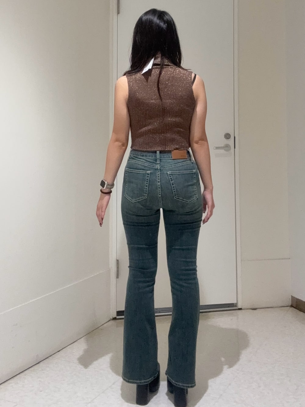 ブラック系のブーツ、ブルー系のデニムパンツ、ブラウン系のタンクトップを着用したレディースの秋コーディネートの3枚目の写真