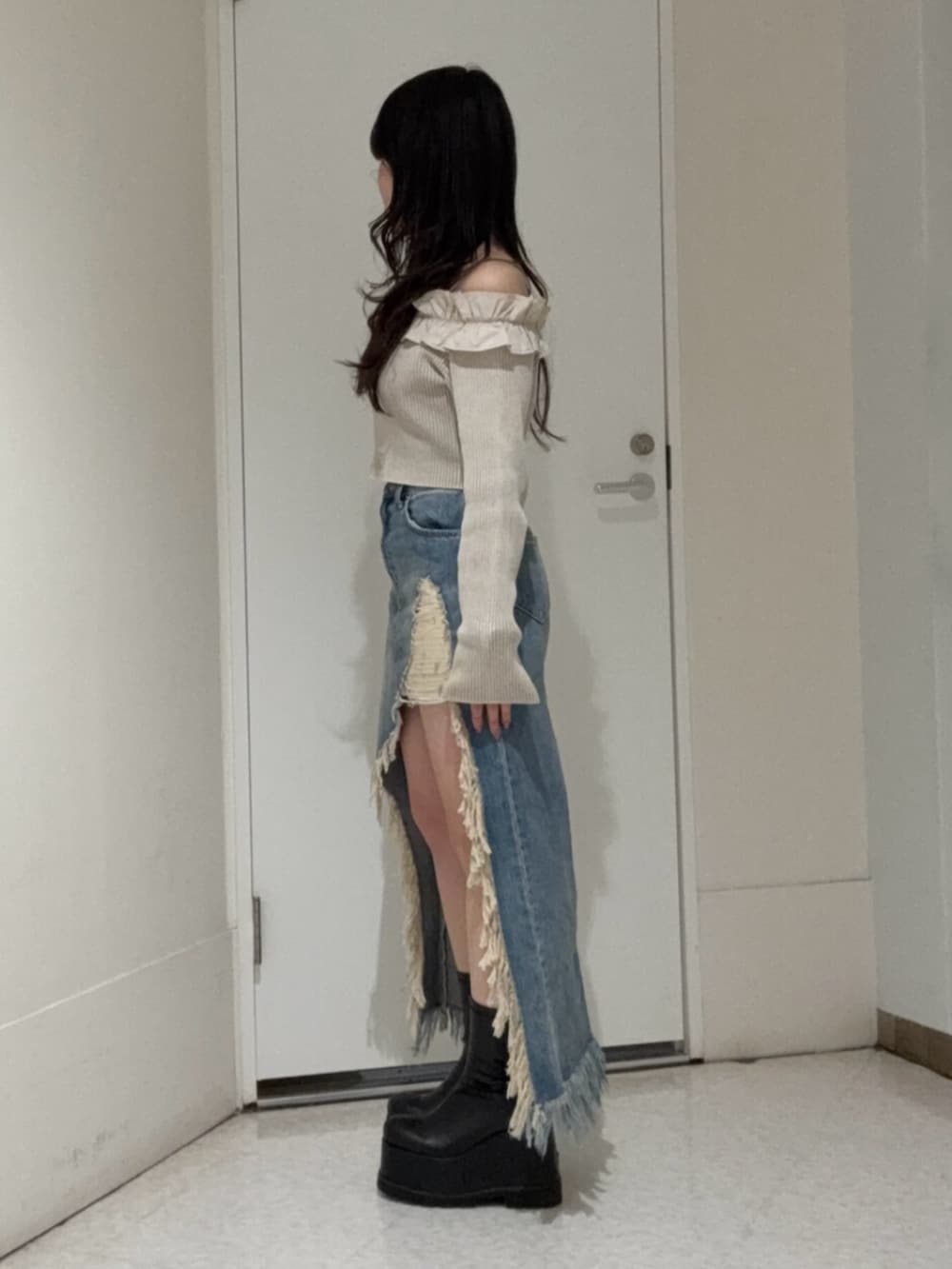 ブラック系のブーツ、ブルー系のデニムスカート、ベージュ系のニット/セーターを着用したレディースの春コーディネートの2枚目の写真