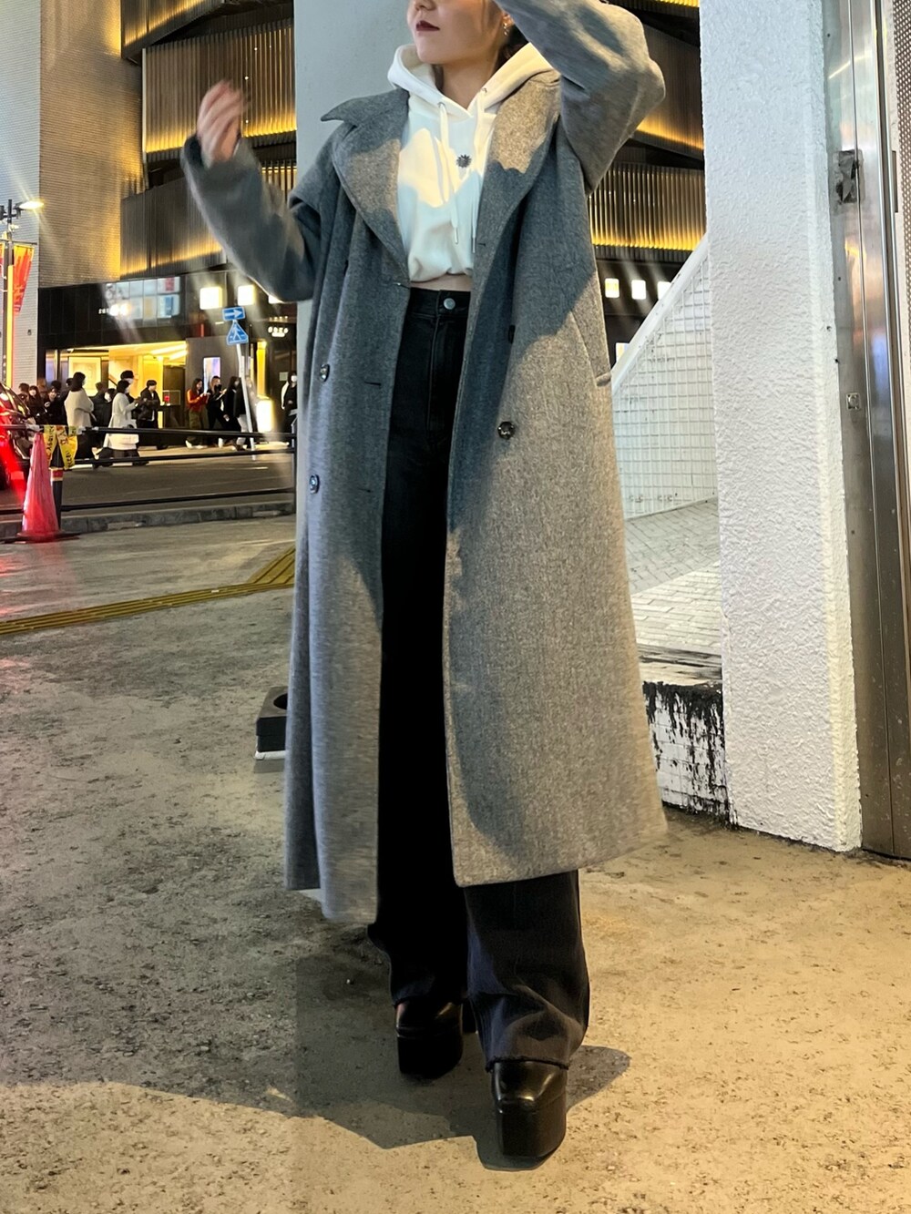 グレー系のチェスターコート、ホワイト系のパーカー、ブラック系のデニムパンツを着用したレディースの冬コーディネートの3枚目の写真