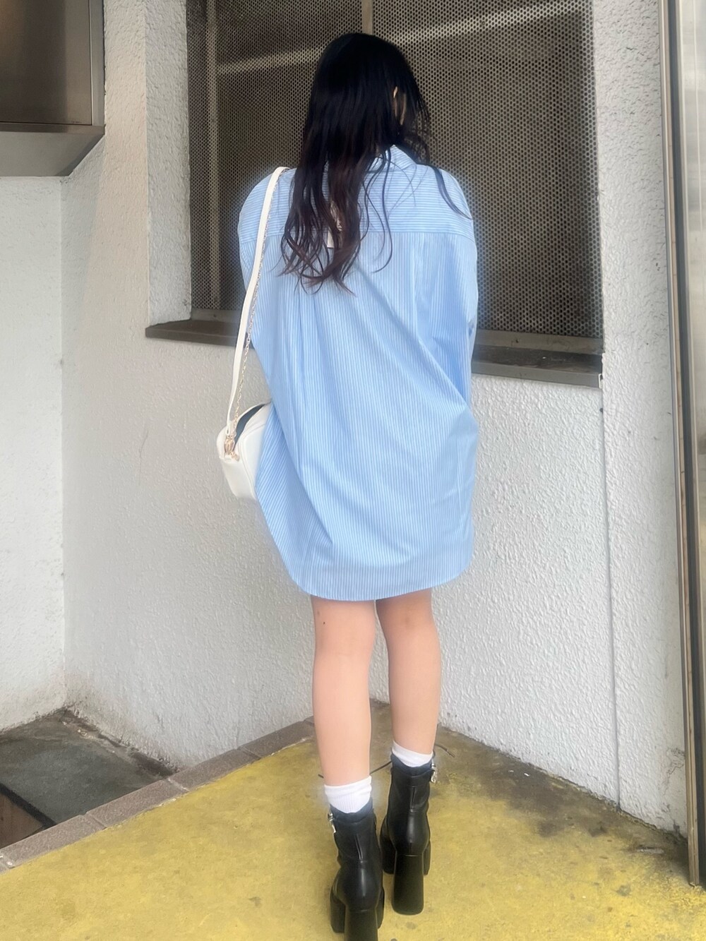 ブルー系のデニムスカート、ブルー系のシャツ/ブラウス、ホワイト系のショルダーバッグを着用したレディースの春コーディネートの4枚目の写真