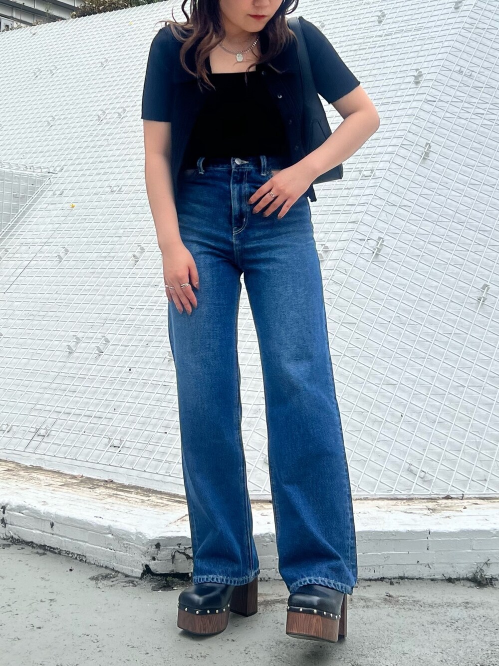 ブルー系のデニムパンツ、ブラック系のニット/セーター、ブラック系のハンドバッグを着用したレディースの春コーディネートの2枚目の写真