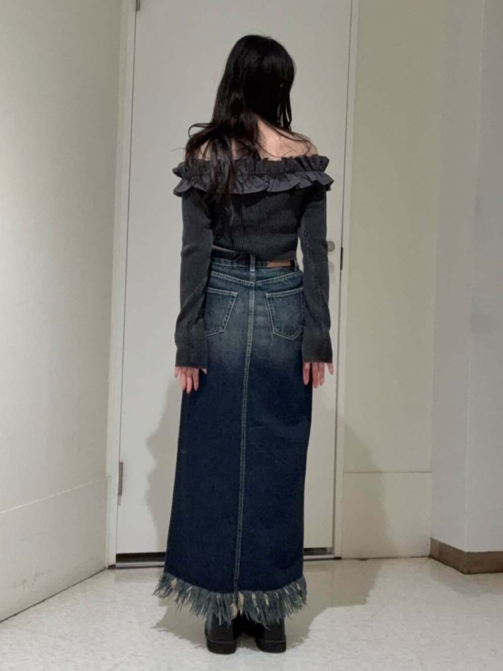 ブラック系のブーツ、ブルー系のデニムスカート、ブラック系のニット/セーターを着用したレディースの冬コーディネートの3枚目の写真