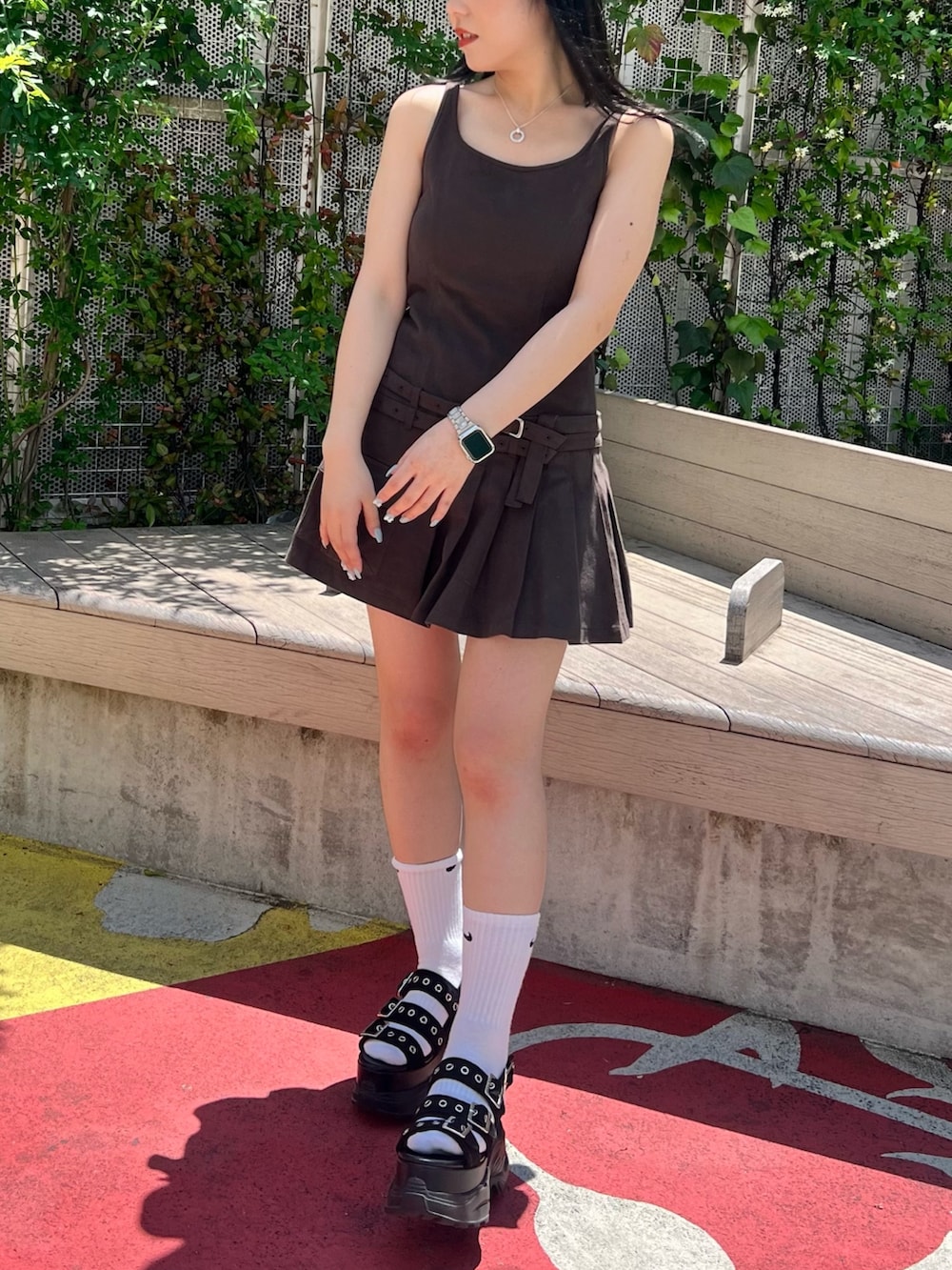 グレー系のジャンパースカート、ブラック系のサンダルを着用したレディースの春コーディネートの2枚目の写真