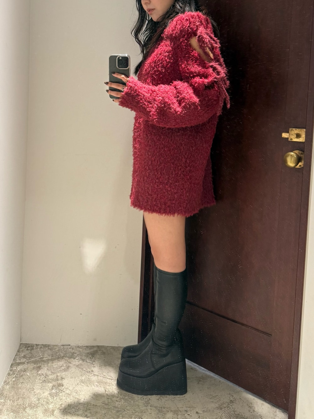 レッド系のワンピース、ブラック系のブーツを着用したレディースの秋コーディネートの2枚目の写真