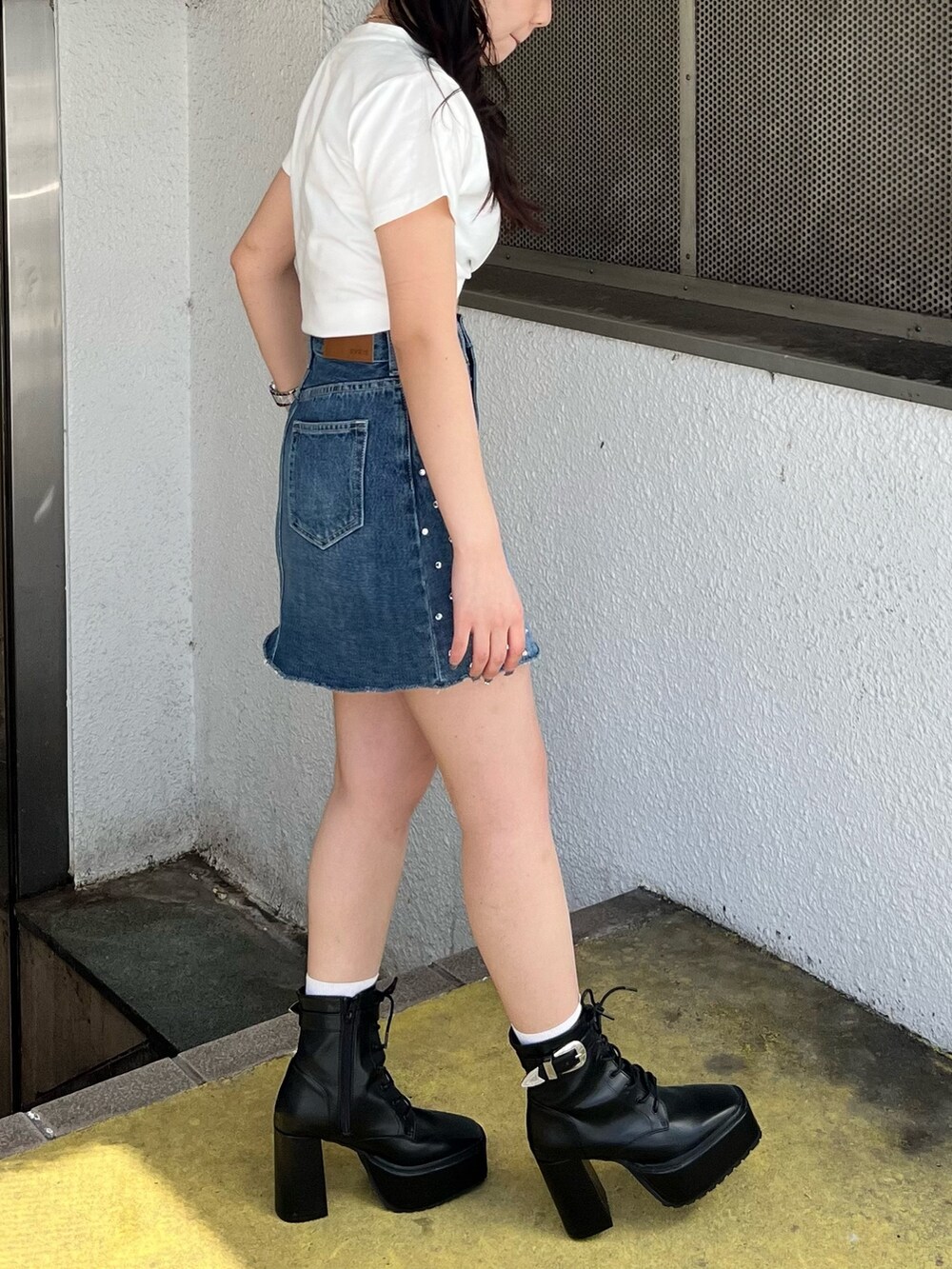 ホワイト系のTシャツ/カットソー、ブルー系のデニムスカート、ブラック系のブーツを着用したレディースの春コーディネートの3枚目の写真