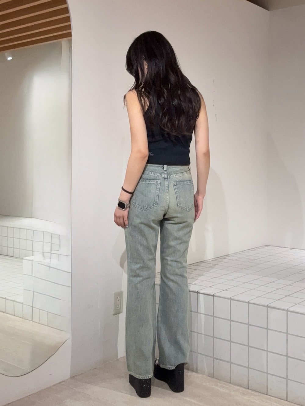 ブラック系のタンクトップ、ブルー系のデニムパンツ、ブラック系のサンダルを着用したレディースの夏コーディネートの3枚目の写真