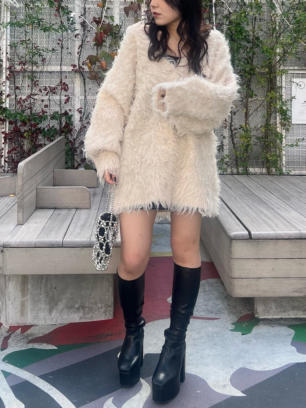 ホワイト系のカーディガン/ボレロ、ブラック系のブーツ、シルバー系のハンドバッグを着用したレディースの冬コーディネートの3枚目の写真