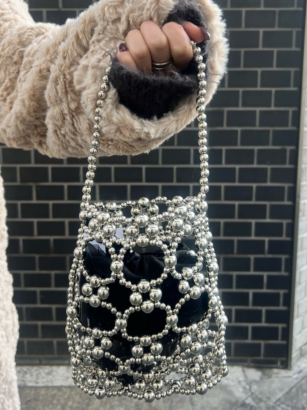 ホワイト系のカーディガン/ボレロ、ブラック系のブーツ、シルバー系のハンドバッグを着用したレディースの冬コーディネートの7枚目の写真