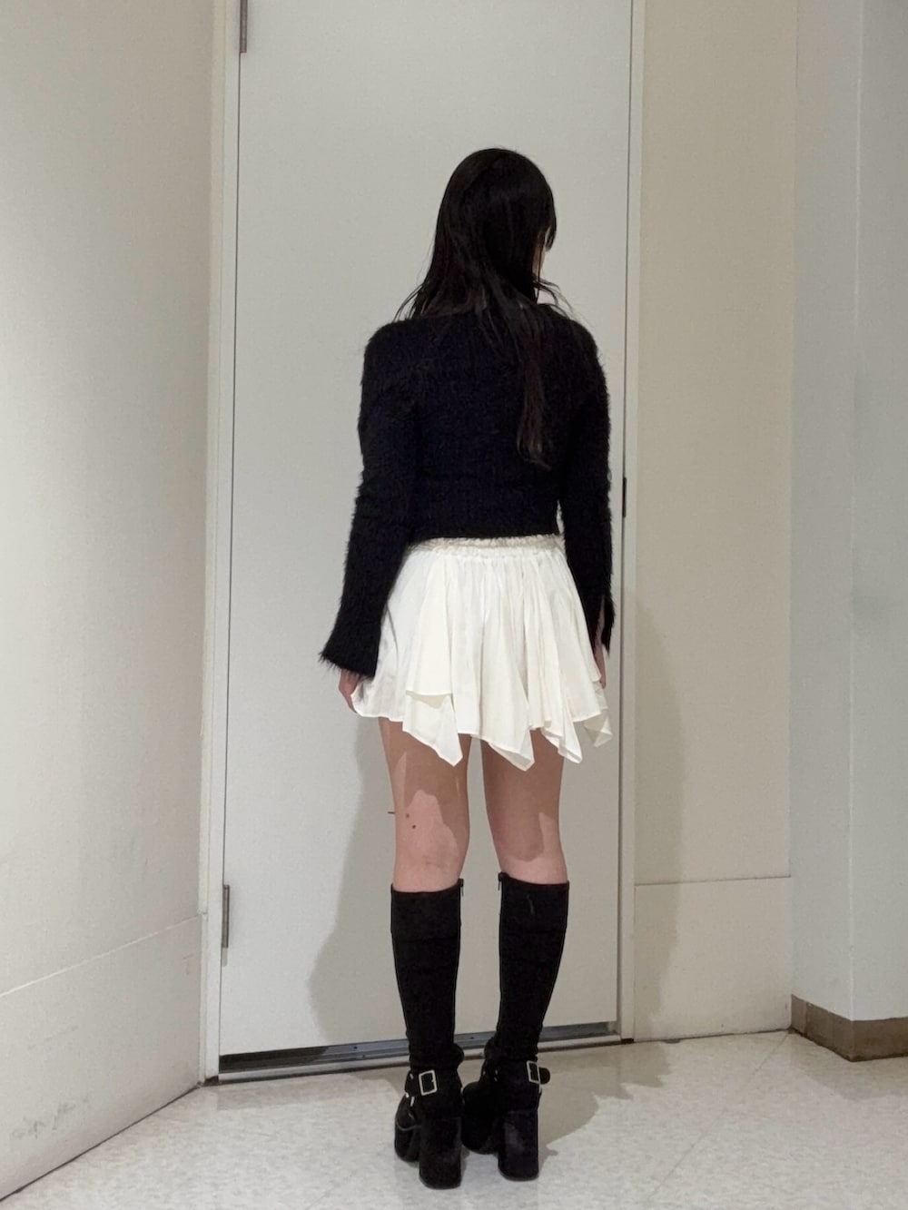 ブラック系のニット/セーター、ホワイト系のスカート、ブラック系のブーツを着用したレディースの冬コーディネートの3枚目の写真