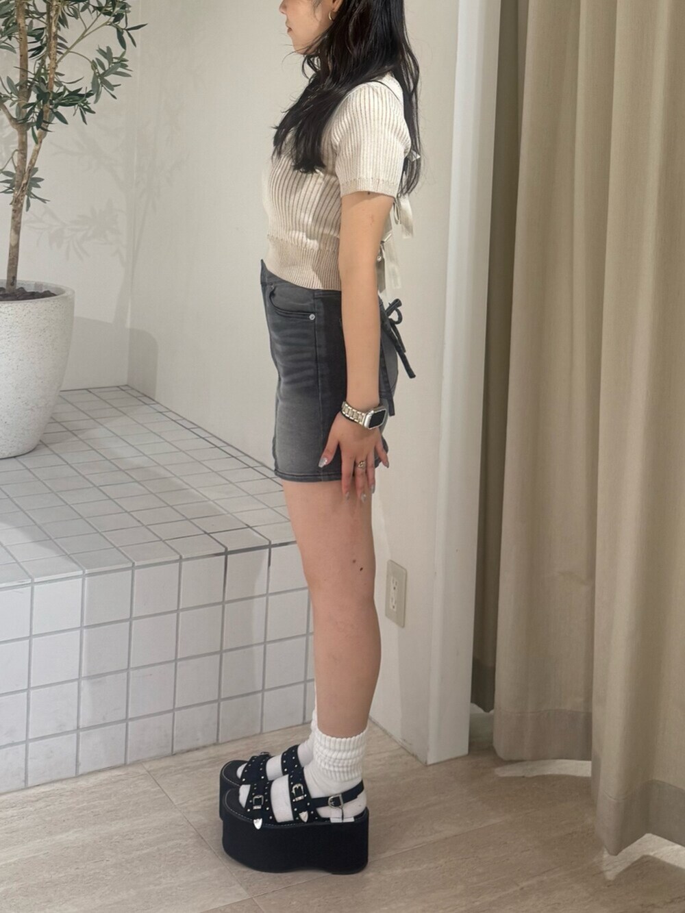 ブラック系のデニムスカート、ブラック系のサンダル、ベージュ系のニット/セーターを着用したレディースの夏コーディネートの2枚目の写真