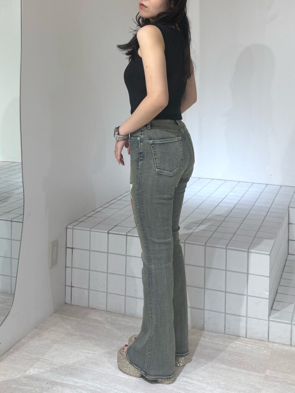 ゴールド系のサンダル、ブルー系のデニムパンツ、ブラック系のニット/セーターを着用したレディースの夏コーディネートの2枚目の写真