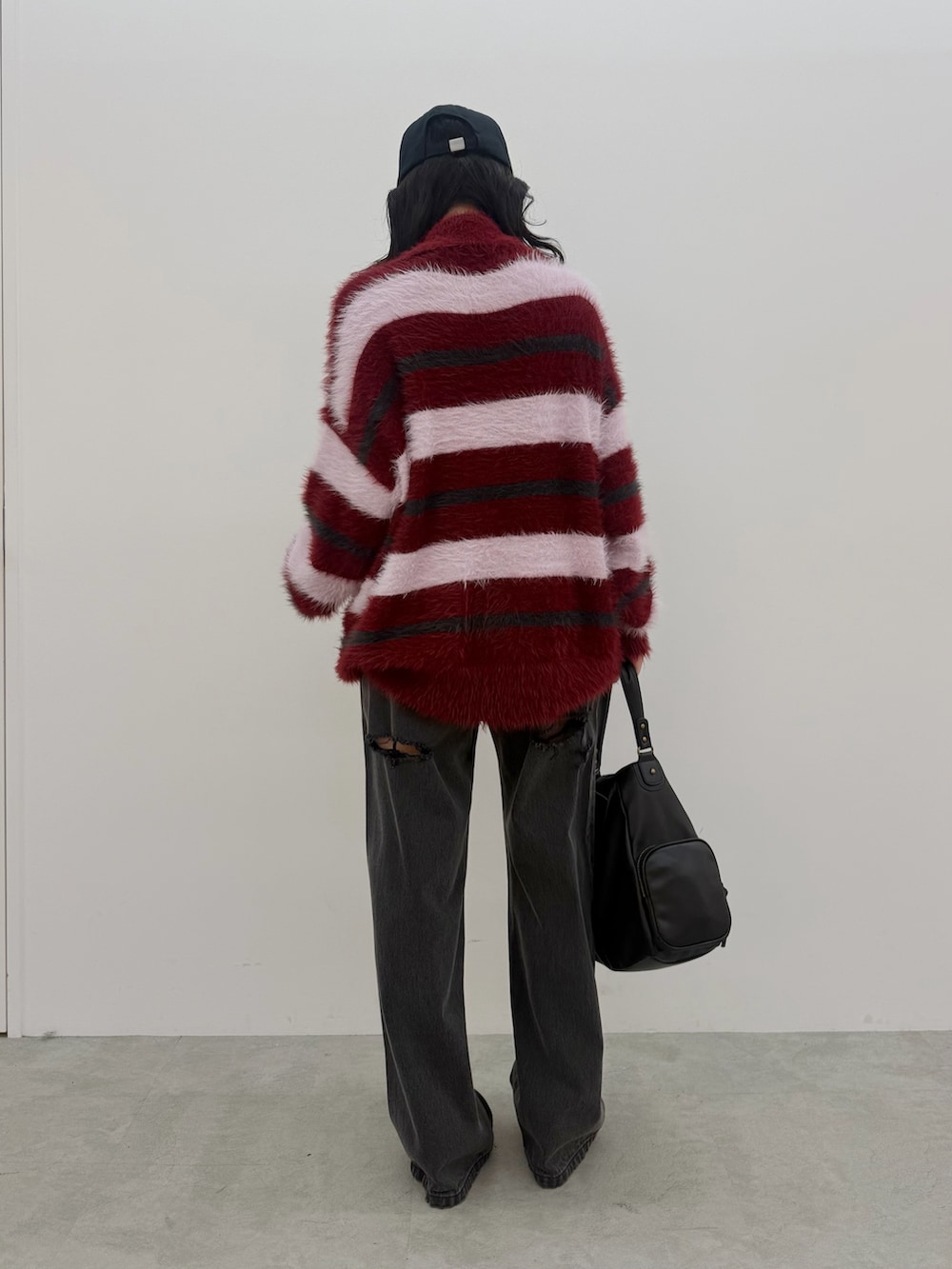 レッド系のニット/セーター、ブラック系のデニムパンツ、レッド系のスニーカーを着用したレディースの秋コーディネートの3枚目の写真