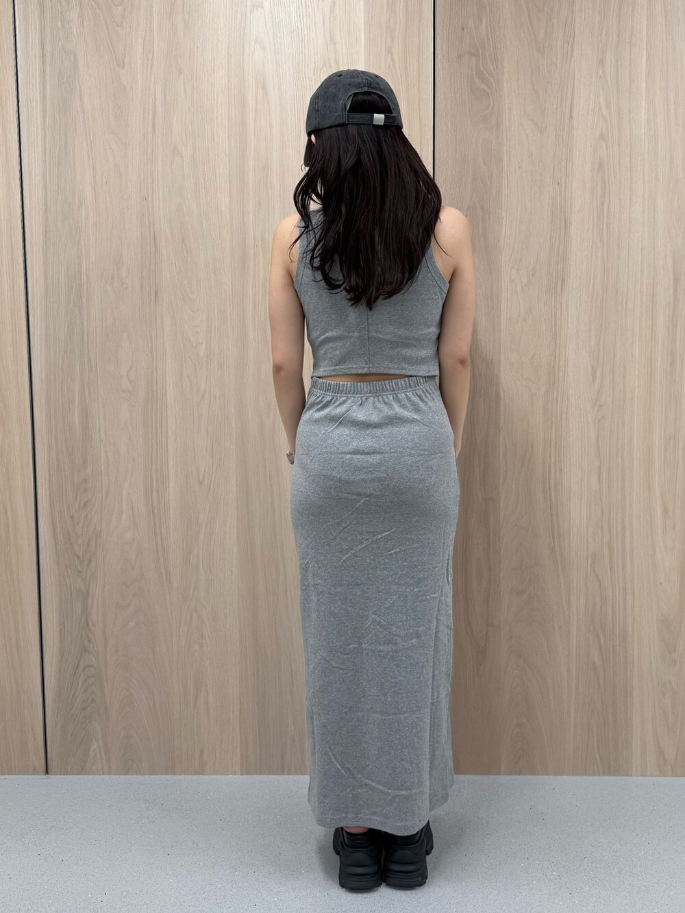 グレー系のワンピース、ブラウン系のサンダル、ブラック系のキャップを着用したレディースの春コーディネートの3枚目の写真