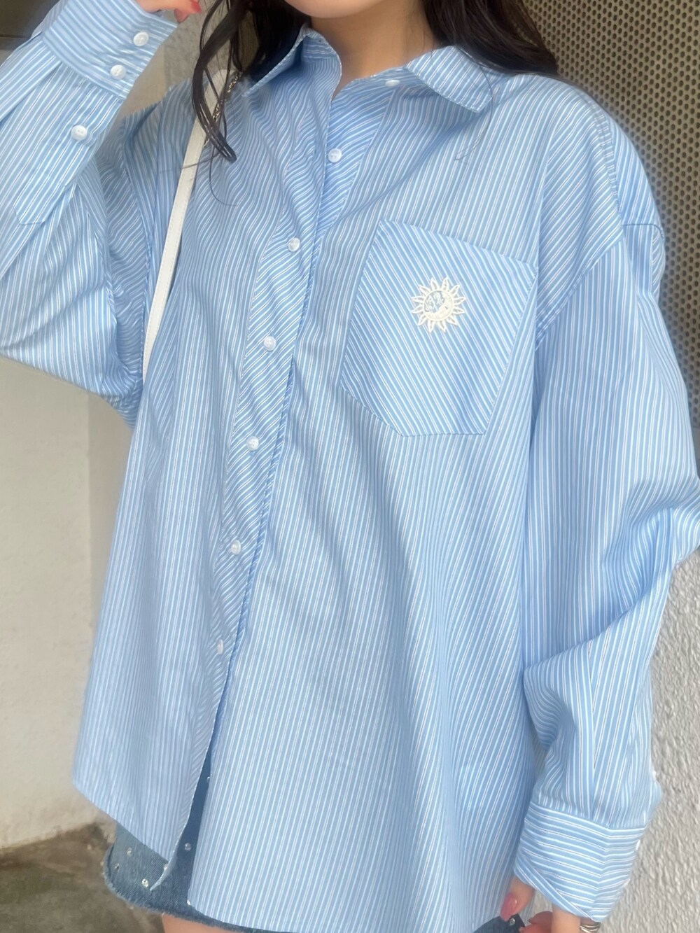 ブルー系のデニムスカート、ブルー系のシャツ/ブラウス、ホワイト系のショルダーバッグを着用したレディースの春コーディネートの5枚目の写真