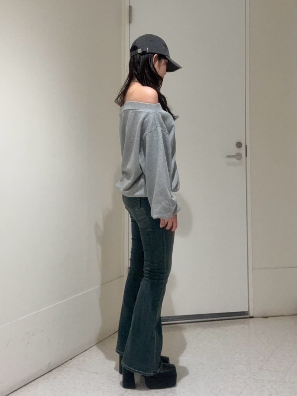 ブラック系のブーツ、グレー系のパーカー、ブルー系のデニムパンツを着用したレディースの秋コーディネートの2枚目の写真