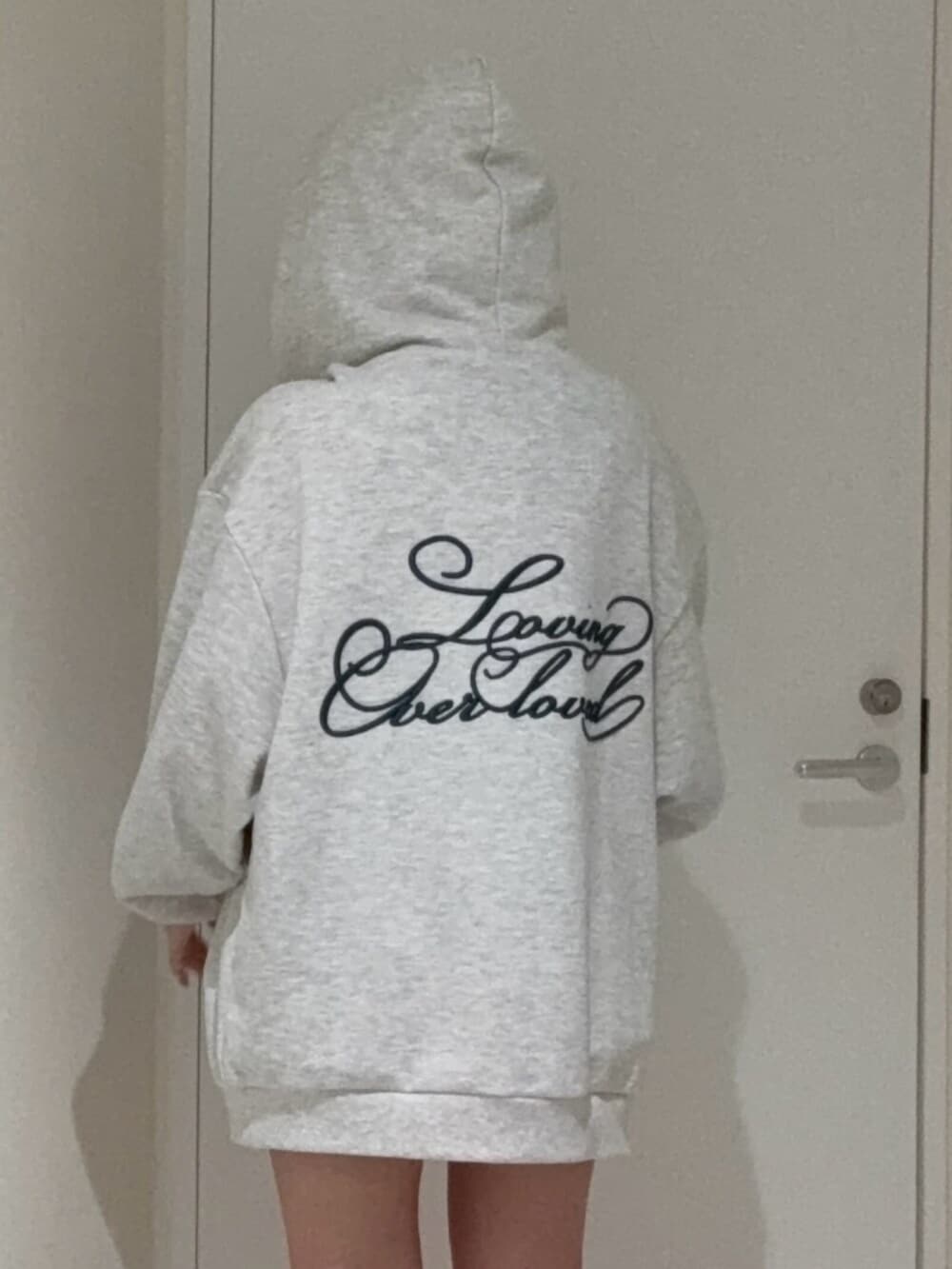 ブラック系のブーツ、グレー系のパーカー、ブラック系のキャップを着用したレディースの春コーディネートの4枚目の写真