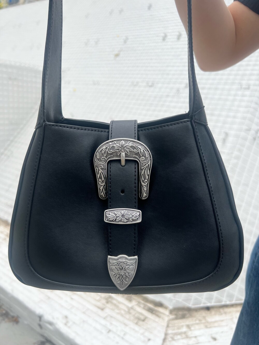 ブルー系のデニムパンツ、ブラック系のニット/セーター、ブラック系のハンドバッグを着用したレディースの春コーディネートの7枚目の写真