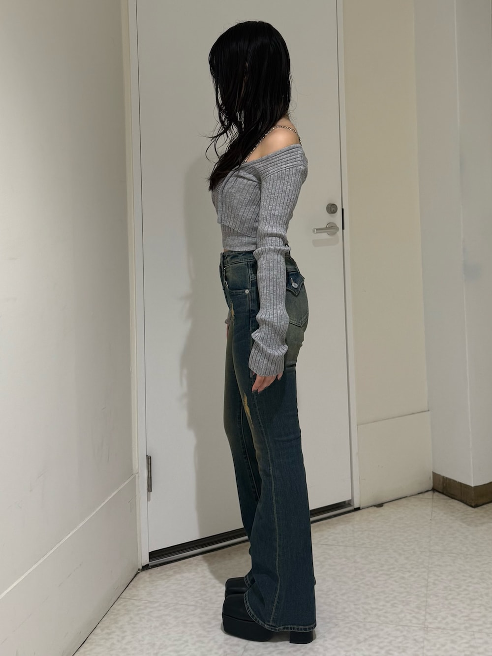 グレー系のニット/セーター、ブルー系のデニムパンツ、ブラック系のブーツを着用したレディースの夏コーディネートの2枚目の写真