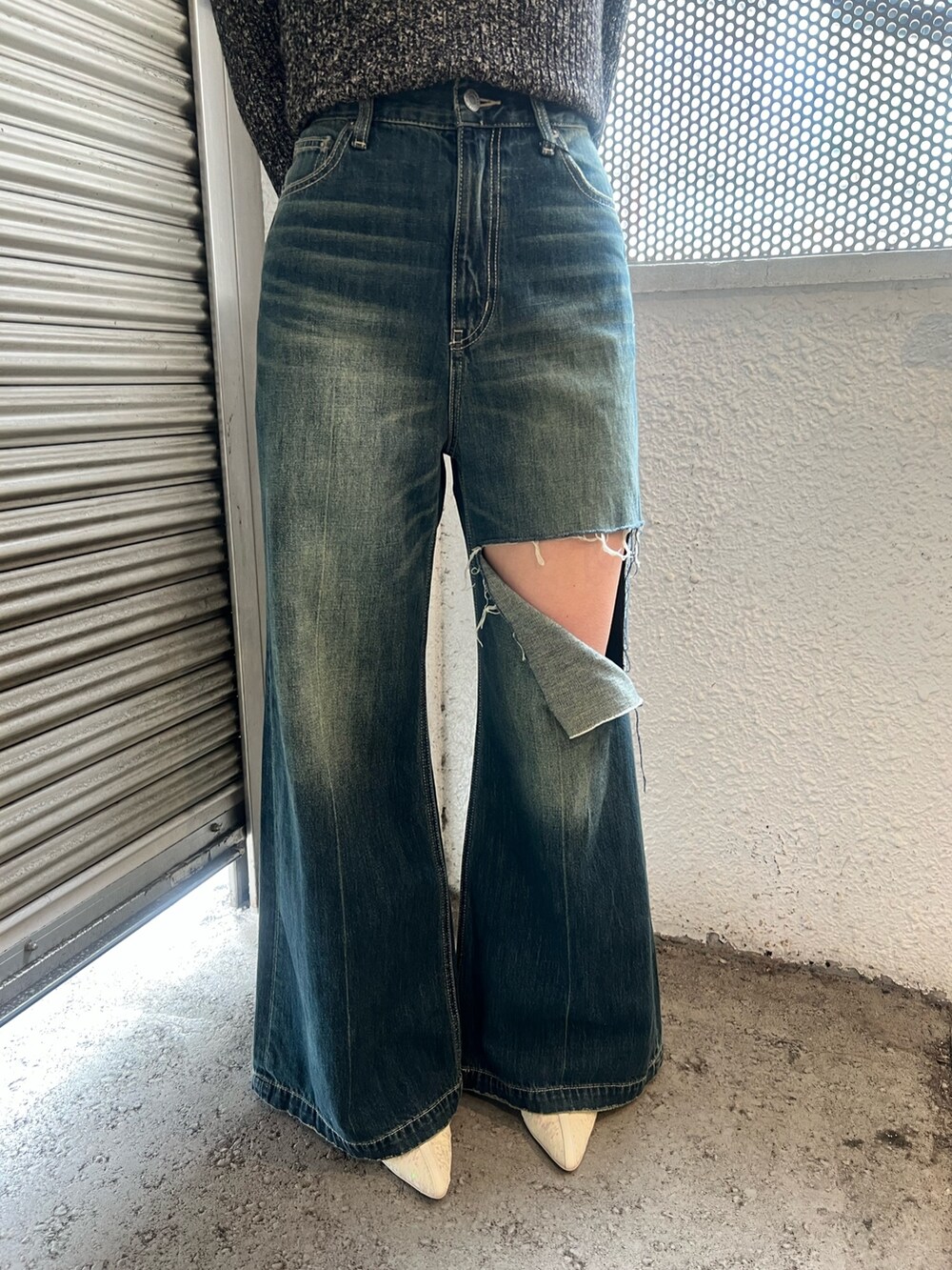 ブルー系のデニムパンツ、ホワイト系のブーツ、ブラック系のニット/セーターを着用したレディースの春コーディネートの6枚目の写真