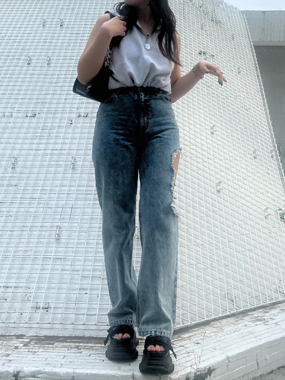 ブルー系のデニムパンツ、ブラック系のハンドバッグ、グレー系のタンクトップを着用したレディースの夏コーディネートの2枚目の写真