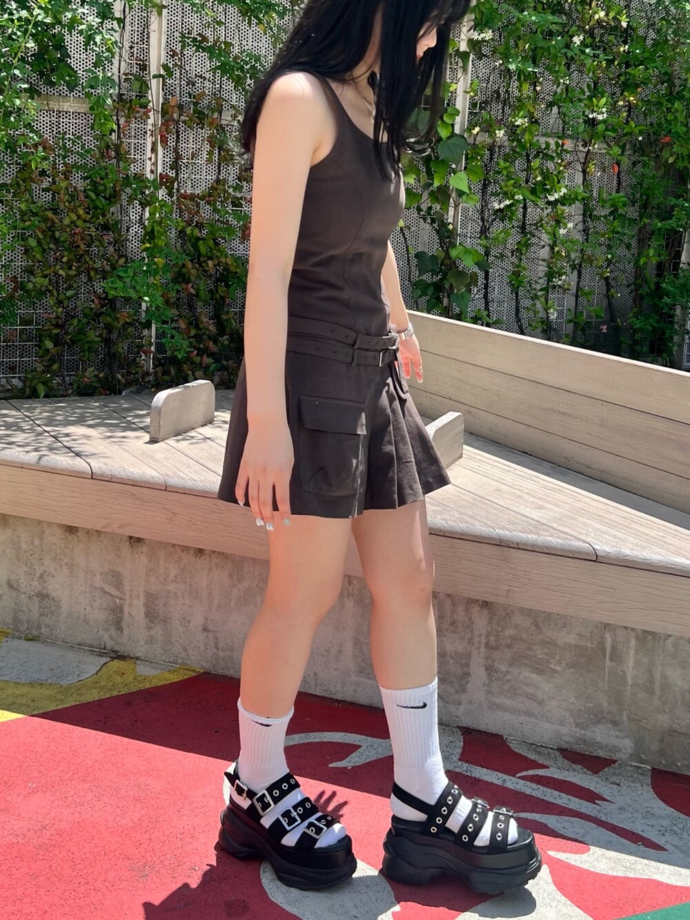 グレー系のジャンパースカート、ブラック系のサンダルを着用したレディースの春コーディネートの3枚目の写真