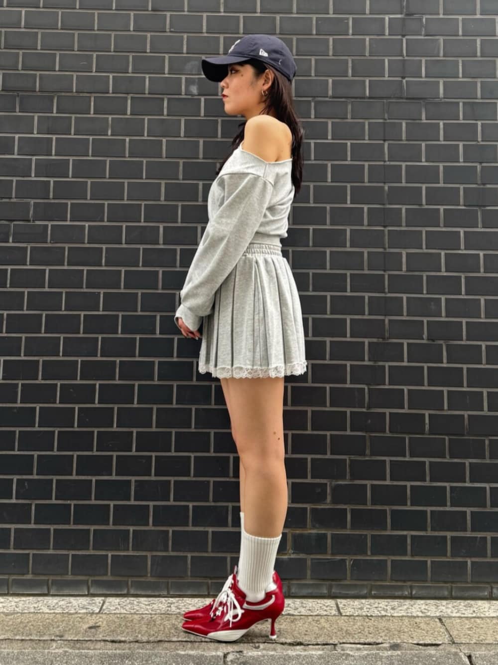 レッド系のパンプス、グレー系のスウェット、グレー系のスカートを着用したレディースの春コーディネートの2枚目の写真