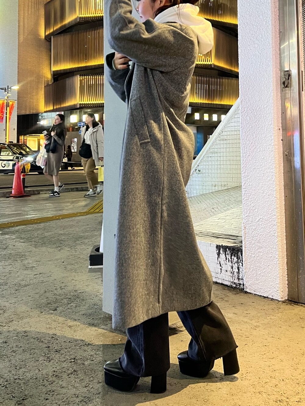 グレー系のチェスターコート、ホワイト系のパーカー、ブラック系のデニムパンツを着用したレディースの冬コーディネートの5枚目の写真