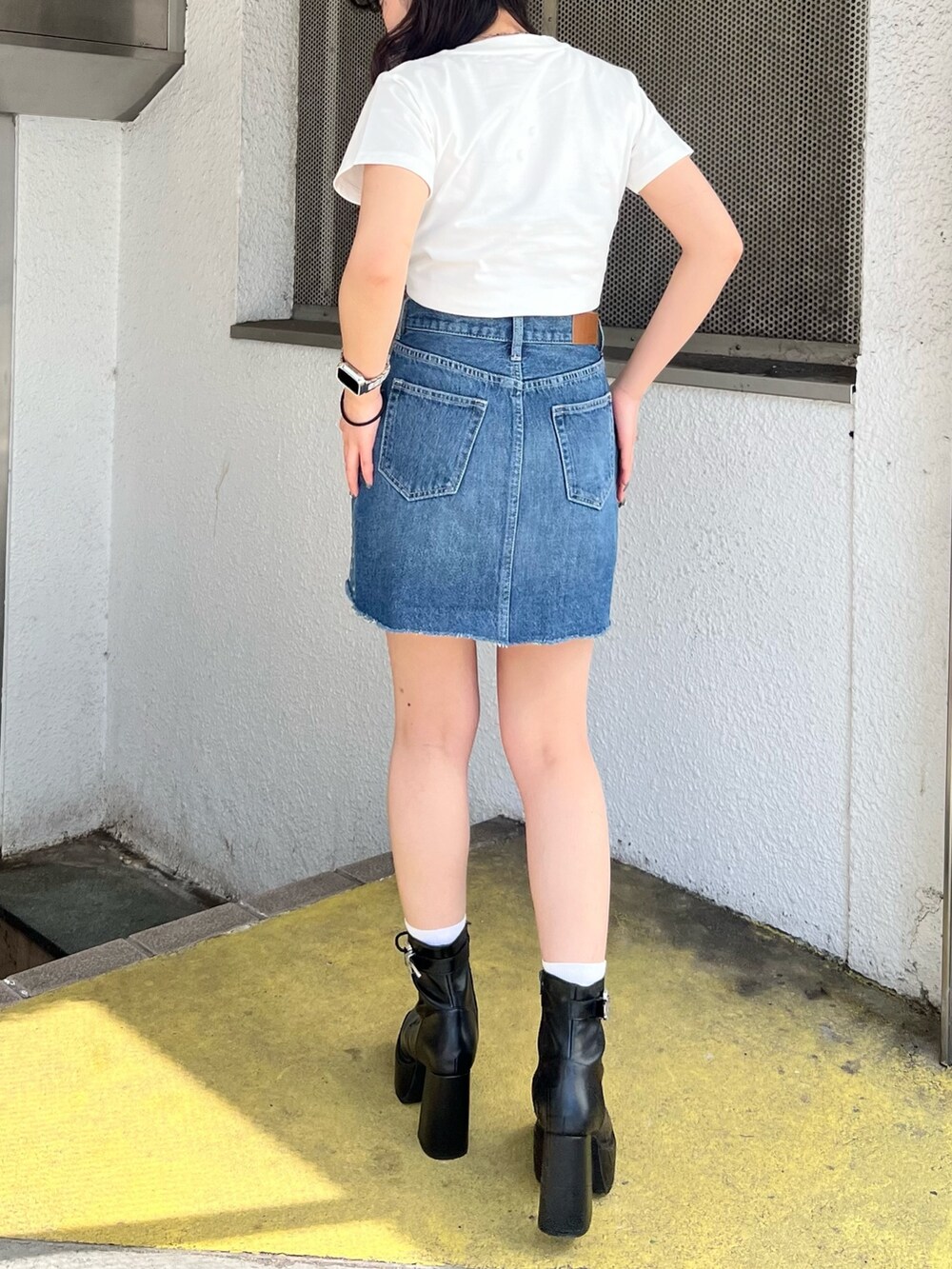 ホワイト系のTシャツ/カットソー、ブルー系のデニムスカート、ブラック系のブーツを着用したレディースの春コーディネートの4枚目の写真