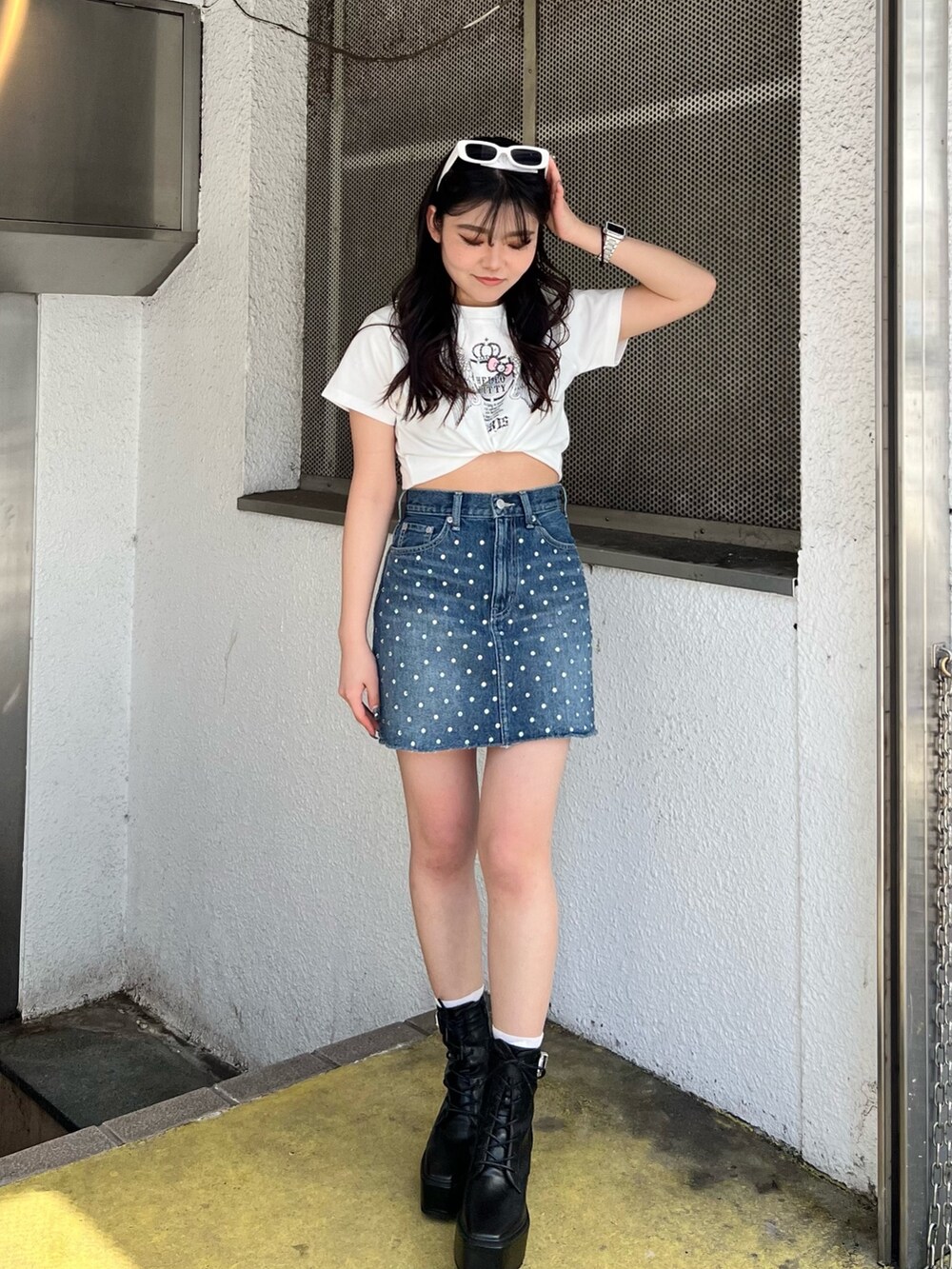 ホワイト系のTシャツ/カットソー、ブルー系のデニムスカート、ブラック系のブーツを着用したレディースの春コーディネートの2枚目の写真