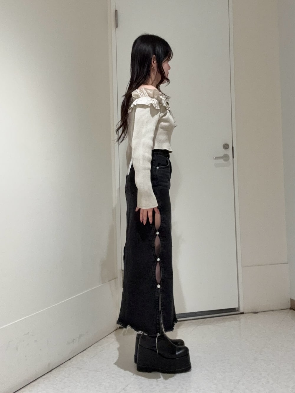 ベージュ系のニット/セーター、ブラック系のデニムスカート、ブラック系のブーツを着用したレディースの春コーディネートの2枚目の写真