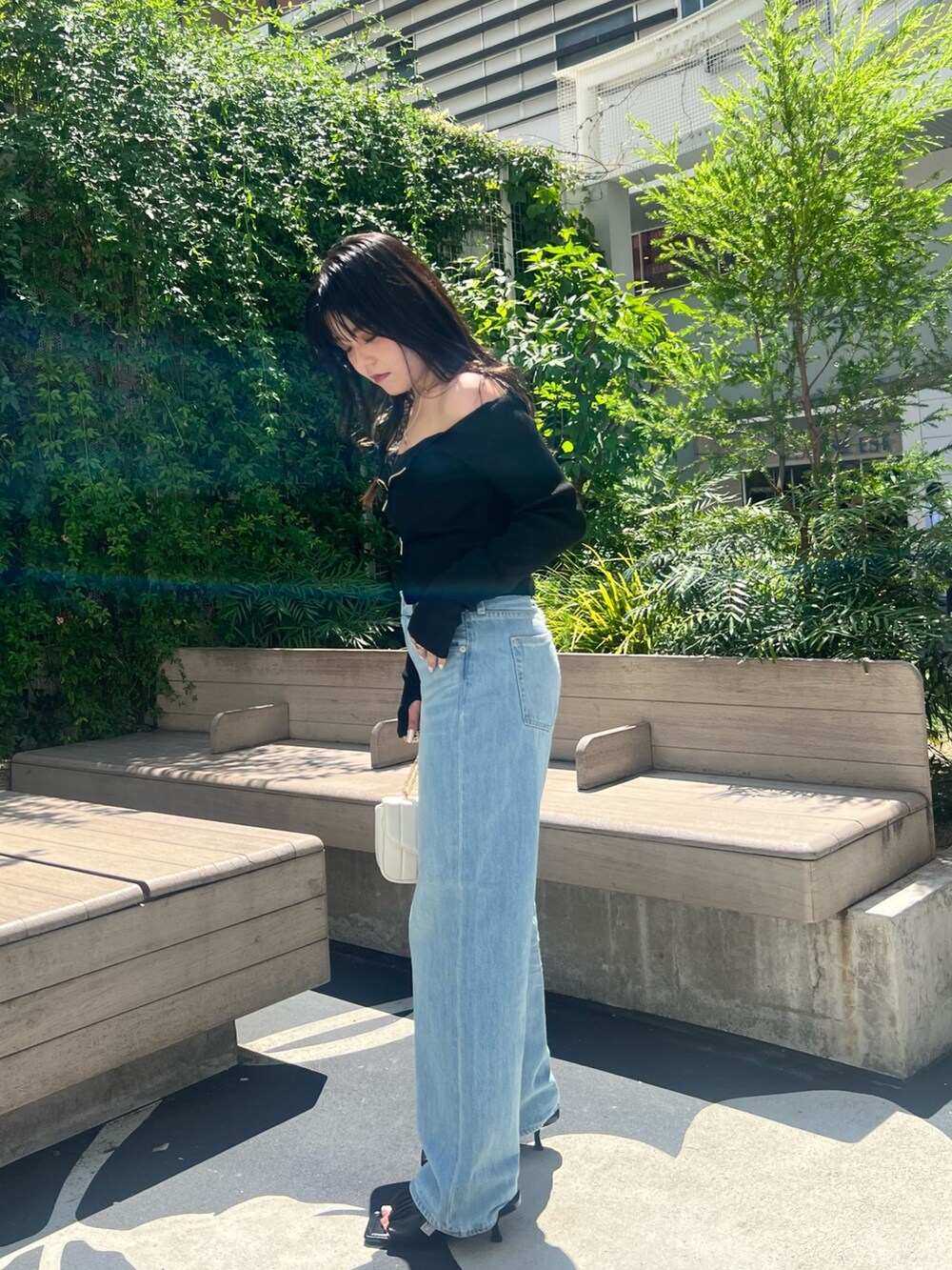 ブルー系のデニムパンツ、ブラック系のニット/セーター、ブラック系のサンダルを着用したレディースの夏コーディネートの4枚目の写真