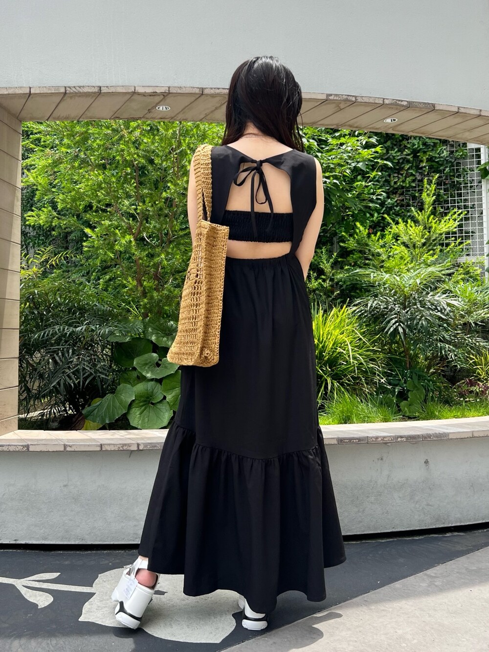 ブラック系のワンピース、ベージュ系のトートバッグ、ホワイト系のサンダルを着用したレディースの夏コーディネートの5枚目の写真