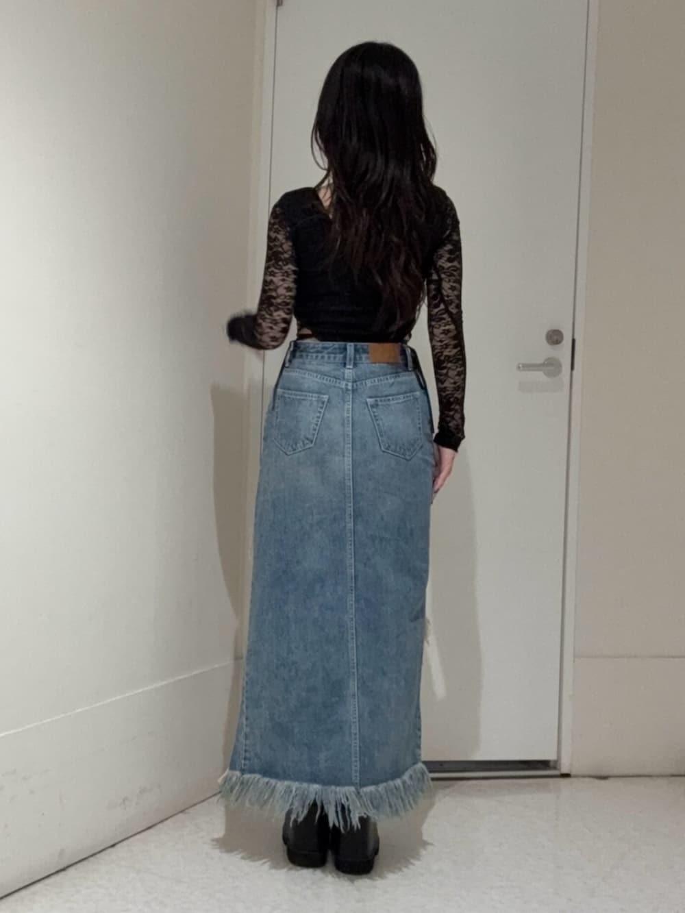 ブラック系のブーツ、ブルー系のデニムスカート、ブラック系のTシャツ/カットソーを着用したレディースの春コーディネートの3枚目の写真