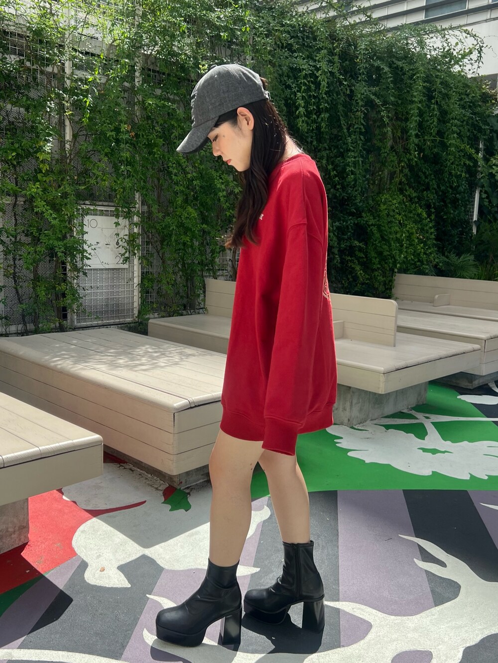 レッド系のスウェット、ブラック系のショルダーバッグ、ブラック系のブーツを着用したレディースの夏コーディネートの3枚目の写真