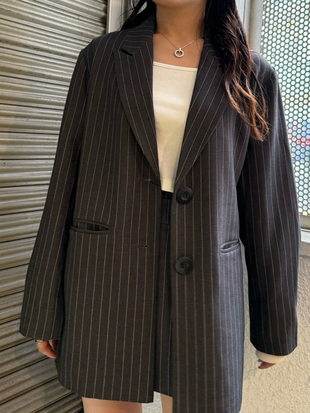 グレー系のテーラードジャケット、グレー系のスカート、ブラック系のブーツを着用したレディースの秋コーディネートの5枚目の写真