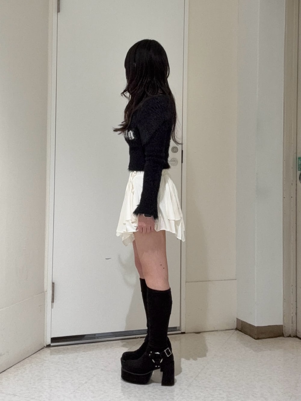 ブラック系のニット/セーター、ホワイト系のスカート、ブラック系のブーツを着用したレディースの冬コーディネートの2枚目の写真