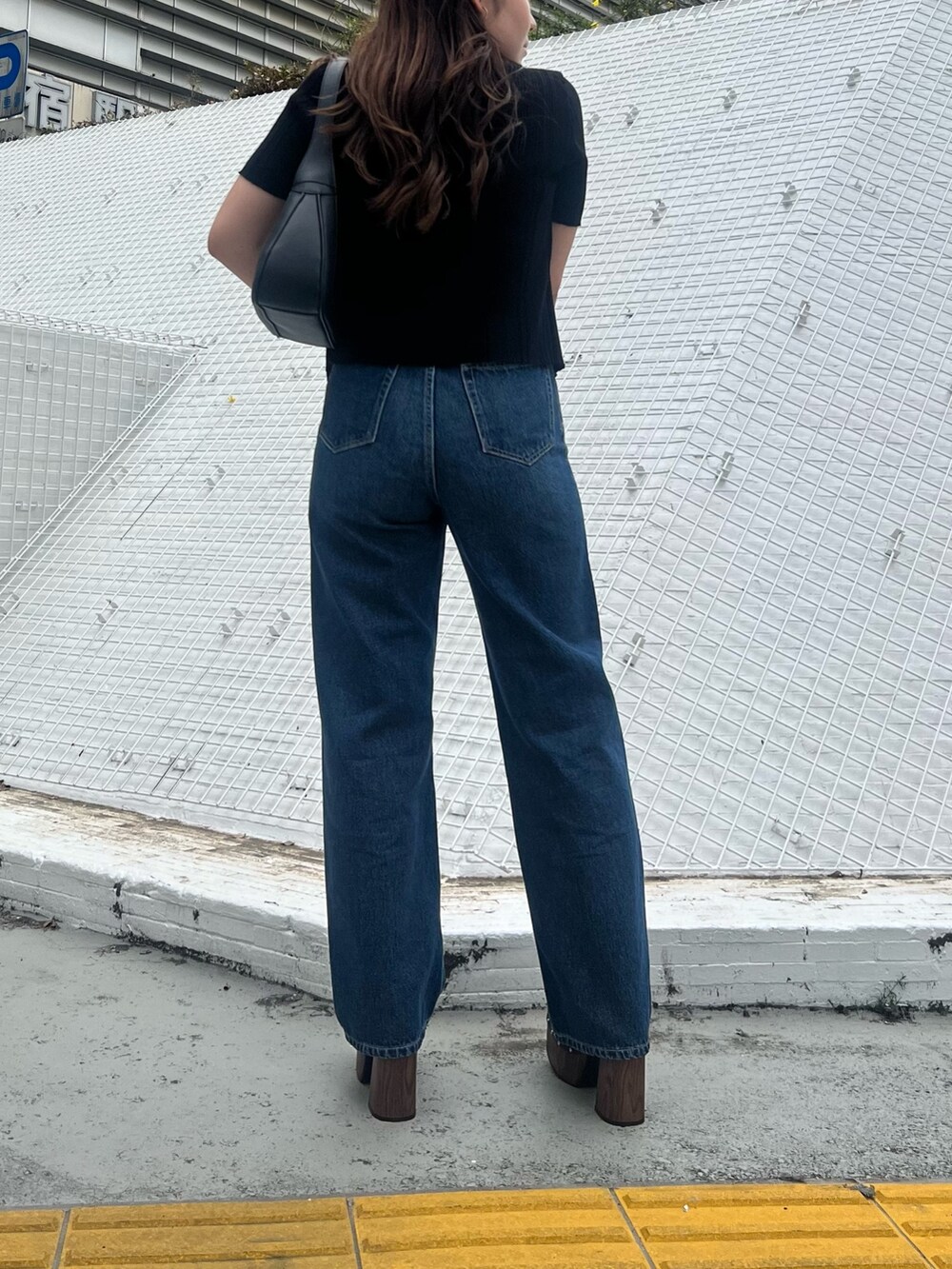 ブルー系のデニムパンツ、ブラック系のニット/セーター、ブラック系のハンドバッグを着用したレディースの春コーディネートの5枚目の写真