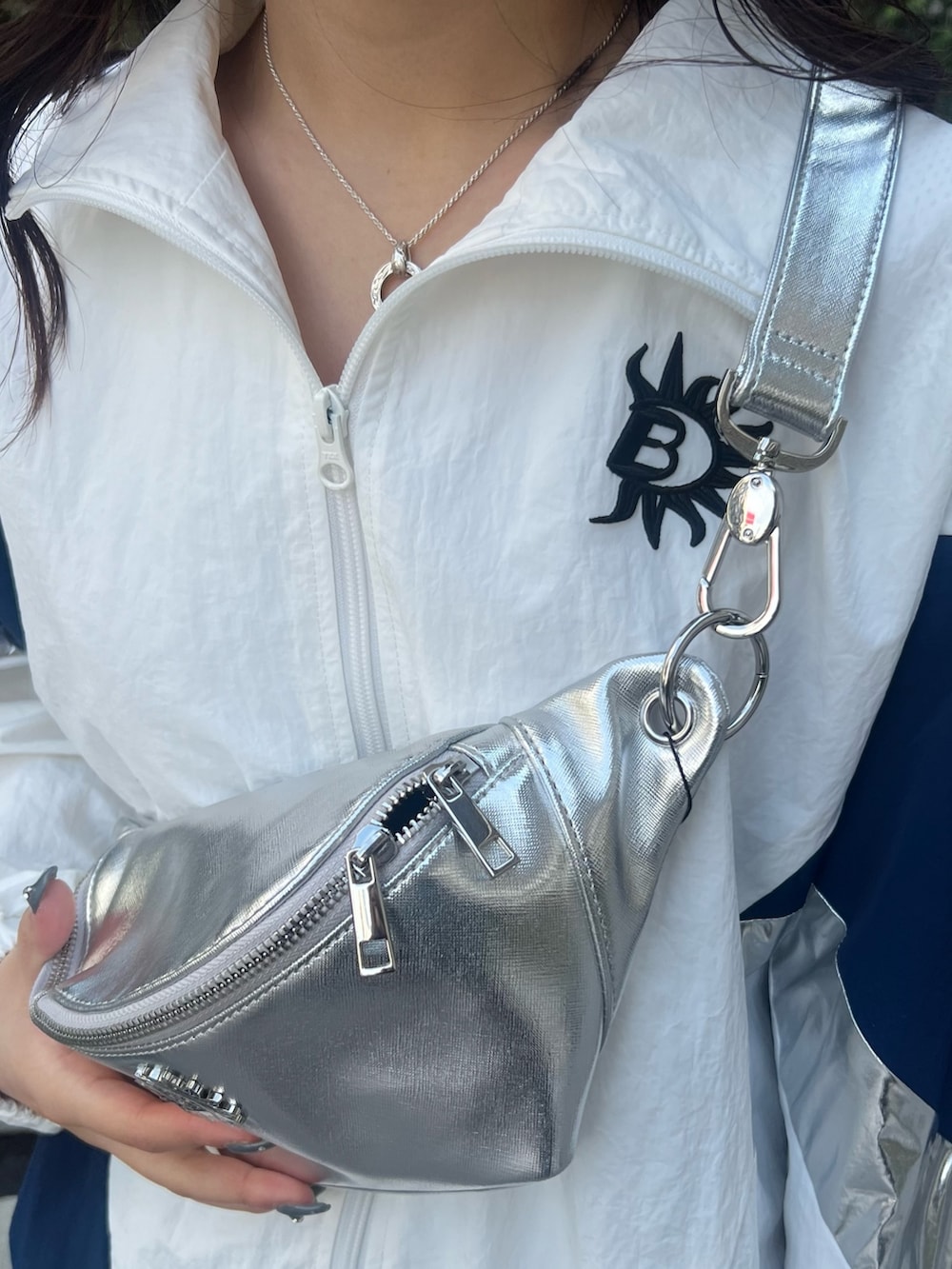 ホワイト系のナイロンジャケット、シルバー系のボディバッグ/ウエストポーチ、ブラック系のブーツを着用したレディースの冬コーディネートの7枚目の写真