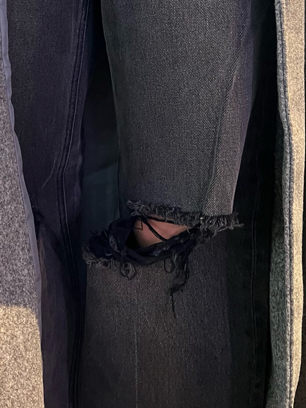 グレー系のチェスターコート、ホワイト系のパーカー、ブラック系のデニムパンツを着用したレディースの冬コーディネートの7枚目の写真