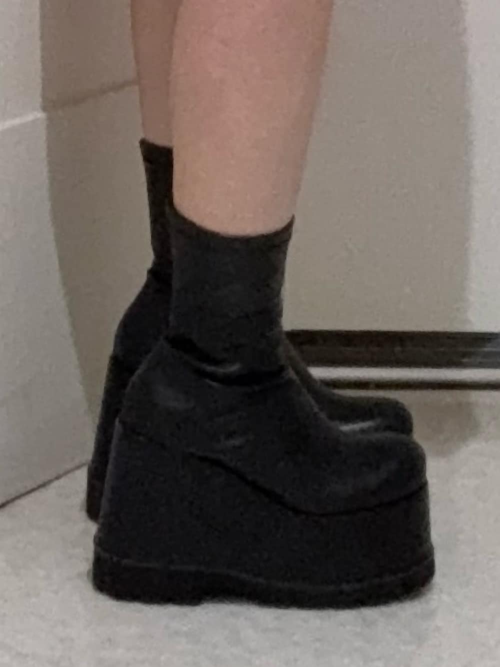 ブラック系のニット/セーター、ブルー系のデニムパンツ、ブラック系のブーツを着用したレディースの春コーディネートの5枚目の写真