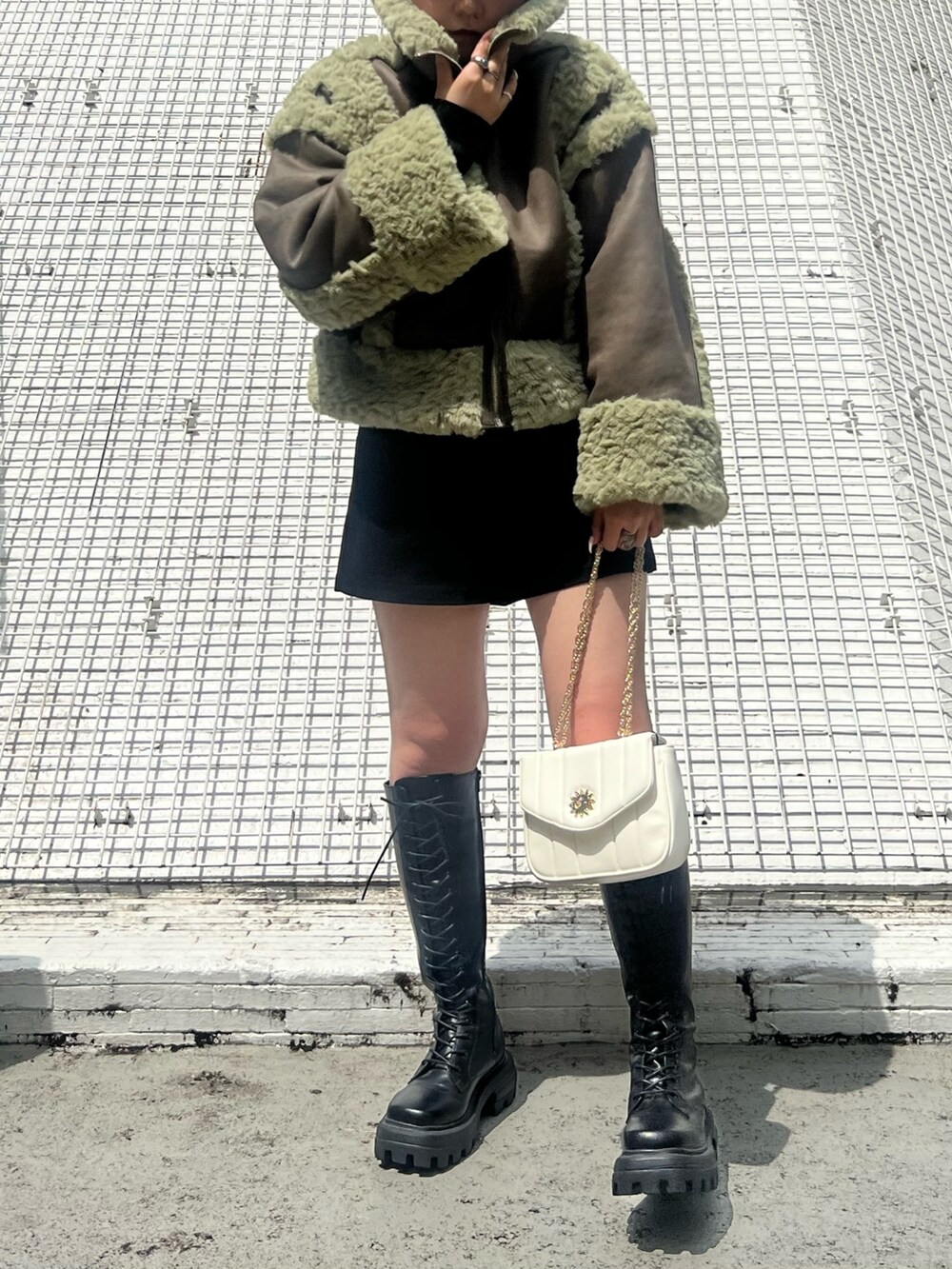 ブラック系のその他パンツ、ブラック系のブーツ、グリーン系のムートンコートを着用したレディースの夏コーディネートの5枚目の写真