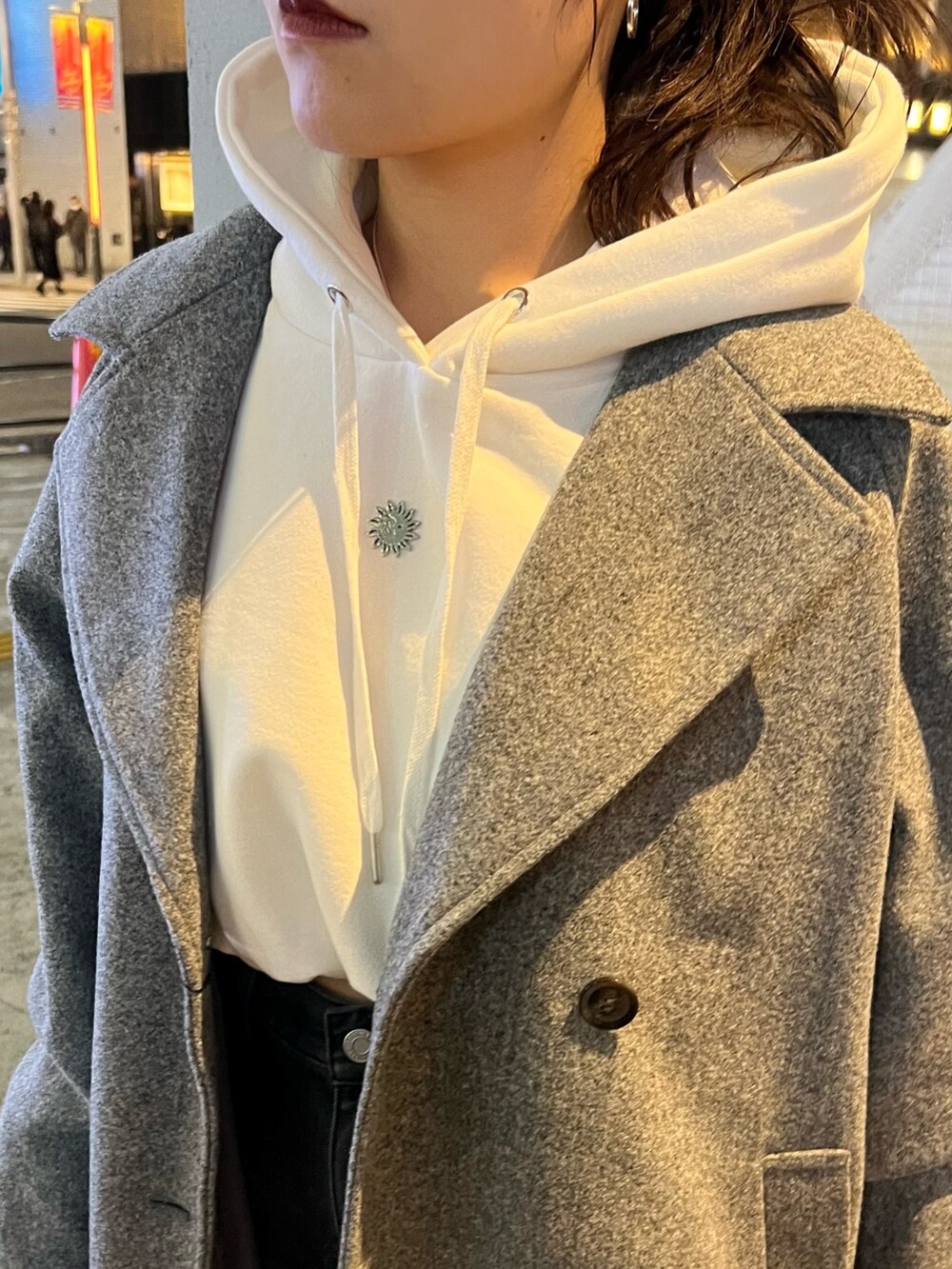 グレー系のチェスターコート、ホワイト系のパーカー、ブラック系のデニムパンツを着用したレディースの冬コーディネートの6枚目の写真