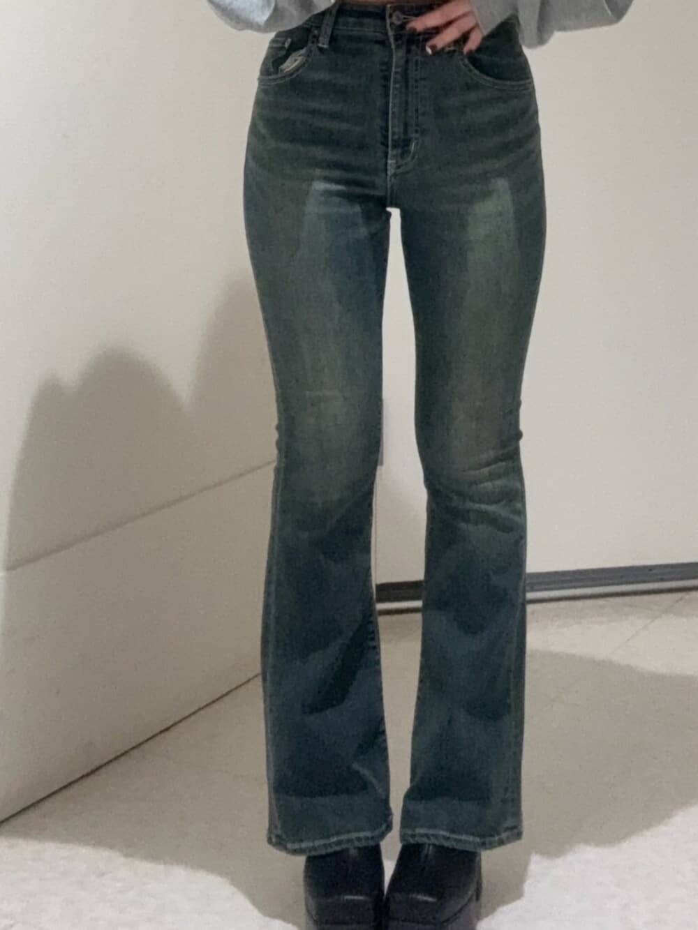 ブラック系のブーツ、グレー系のパーカー、ブルー系のデニムパンツを着用したレディースの秋コーディネートの5枚目の写真