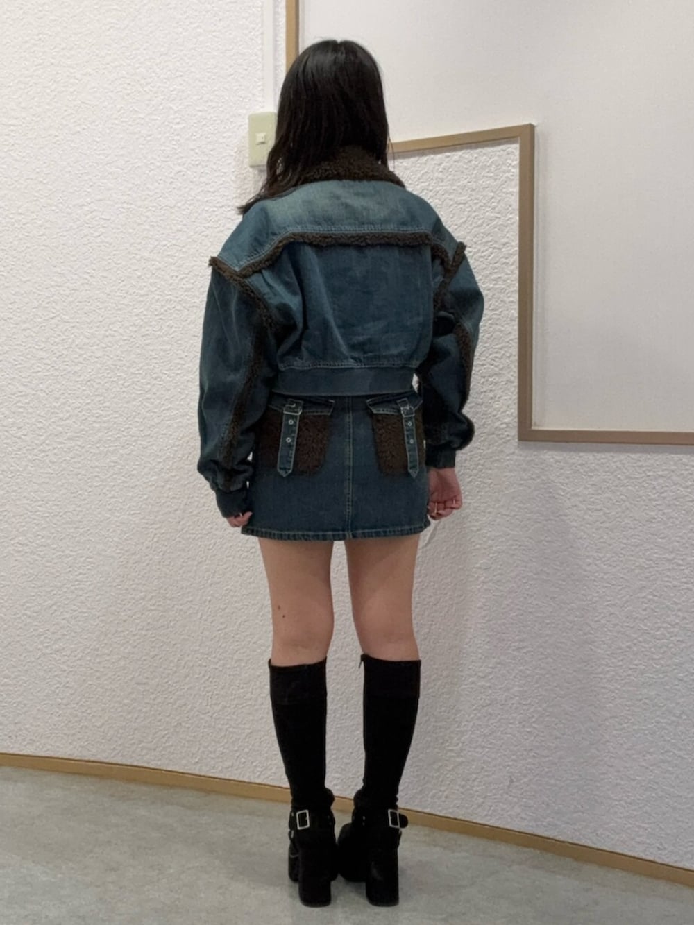 ブラック系のブーツ、ブルー系のブルゾン、ブルー系のデニムスカートを着用したレディースの秋コーディネートの3枚目の写真