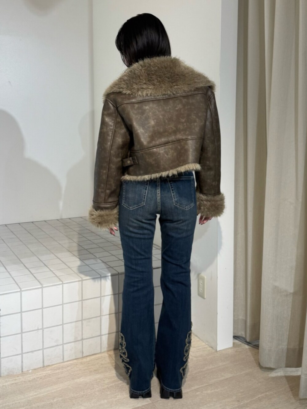 ブルー系のデニムパンツ、ブラック系のブーツ、ブラウン系のブルゾンを着用したレディースの秋コーディネートの3枚目の写真