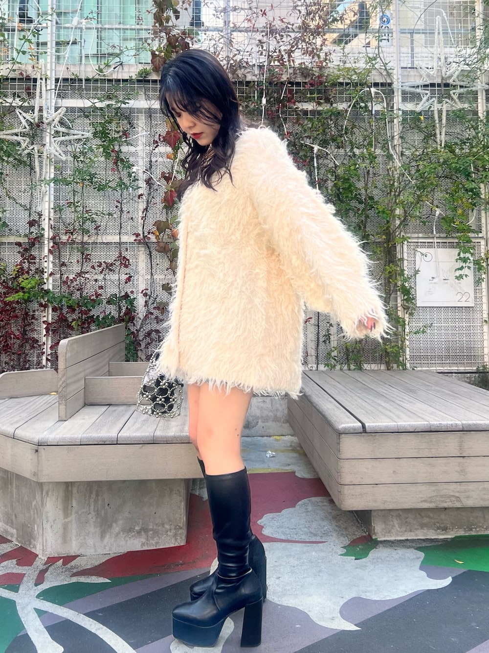 ホワイト系のカーディガン/ボレロ、ブラック系のブーツ、シルバー系のハンドバッグを着用したレディースの冬コーディネートの4枚目の写真