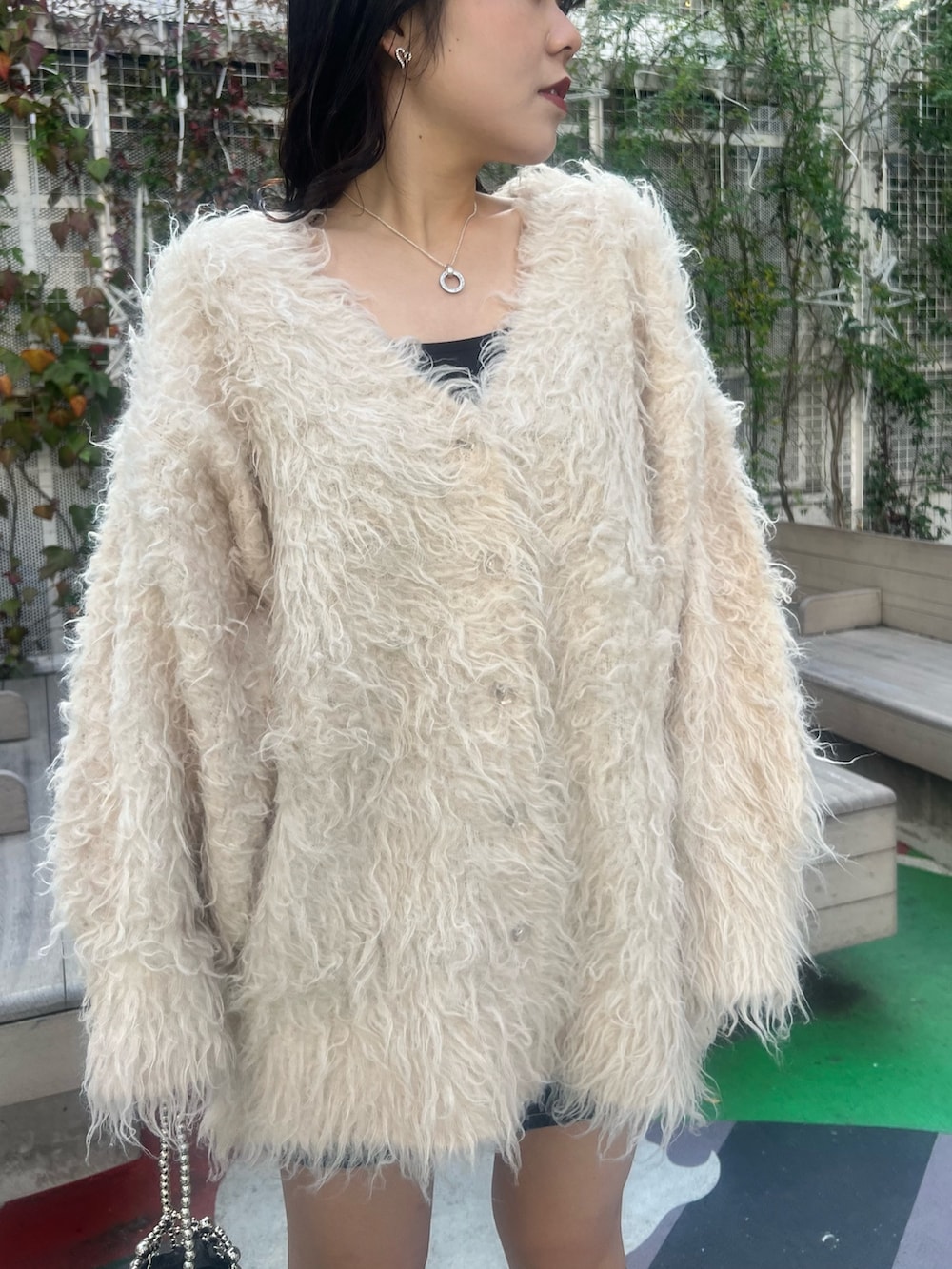 ホワイト系のカーディガン/ボレロ、ブラック系のブーツ、シルバー系のハンドバッグを着用したレディースの冬コーディネートの6枚目の写真